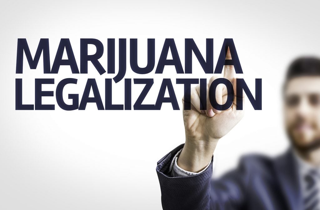 Business man pointing to transparent board with text: Marijuana Legalization