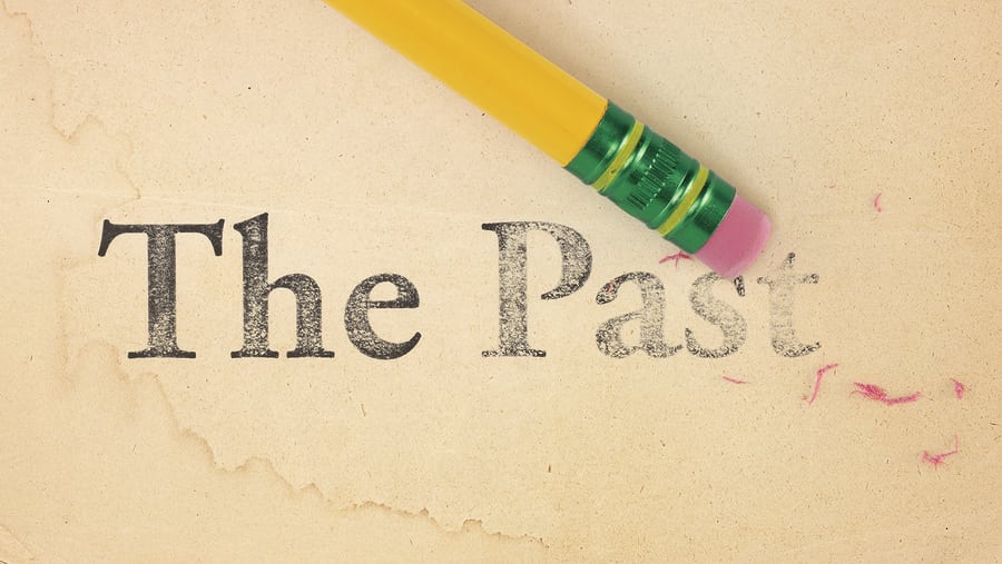 Close up of a yellow pencil erasing the words 'The Past' from old yellowed paper
